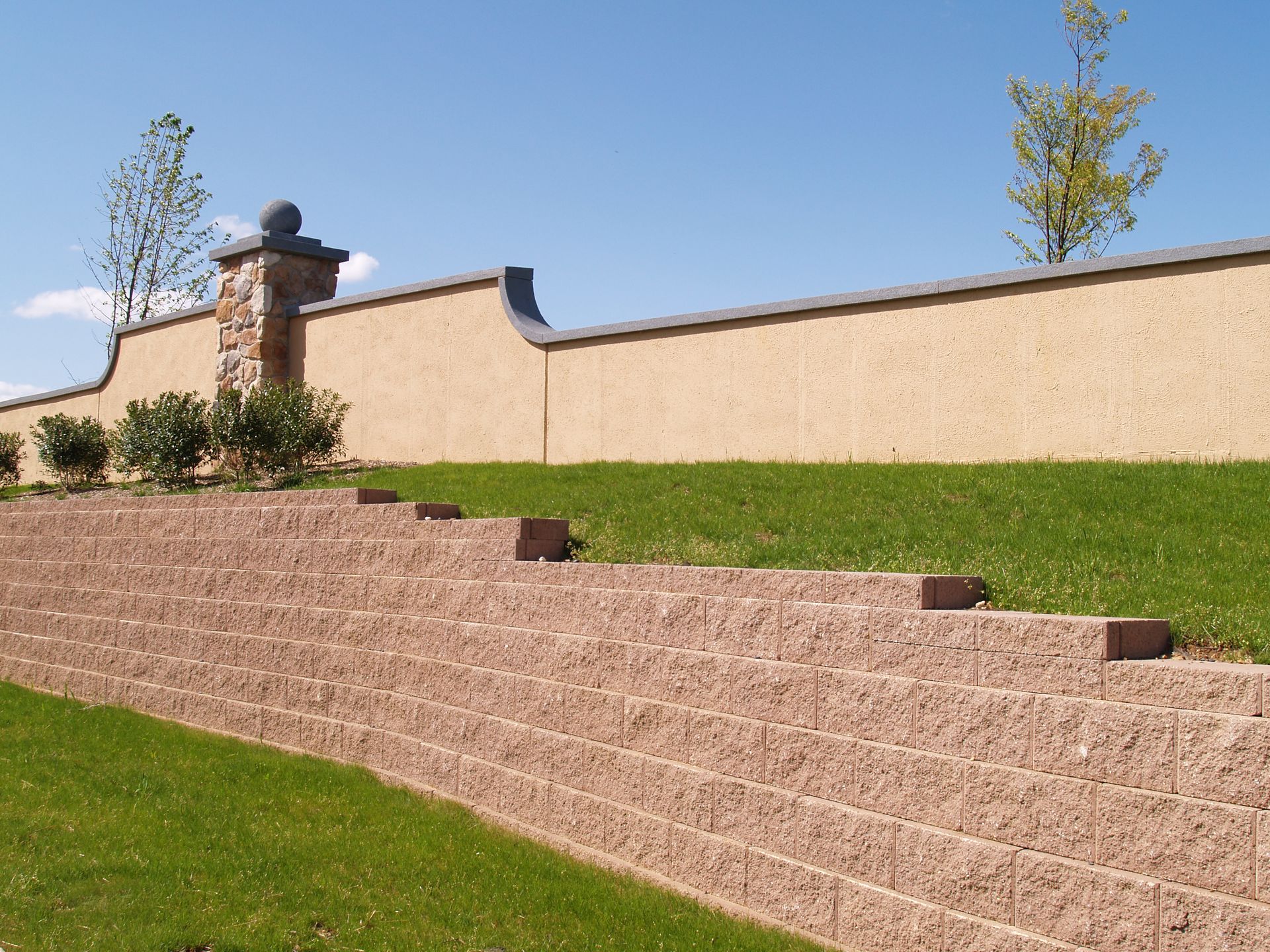 A brick wall surrounds a lush green hillside