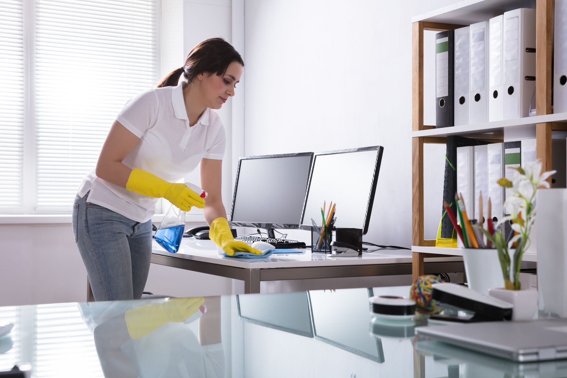 A woman is cleaning a desk in an office.