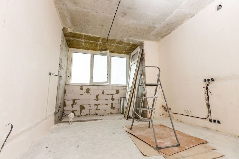 Renovation room with ladder, unfinished walls, and debris near a windowed wall