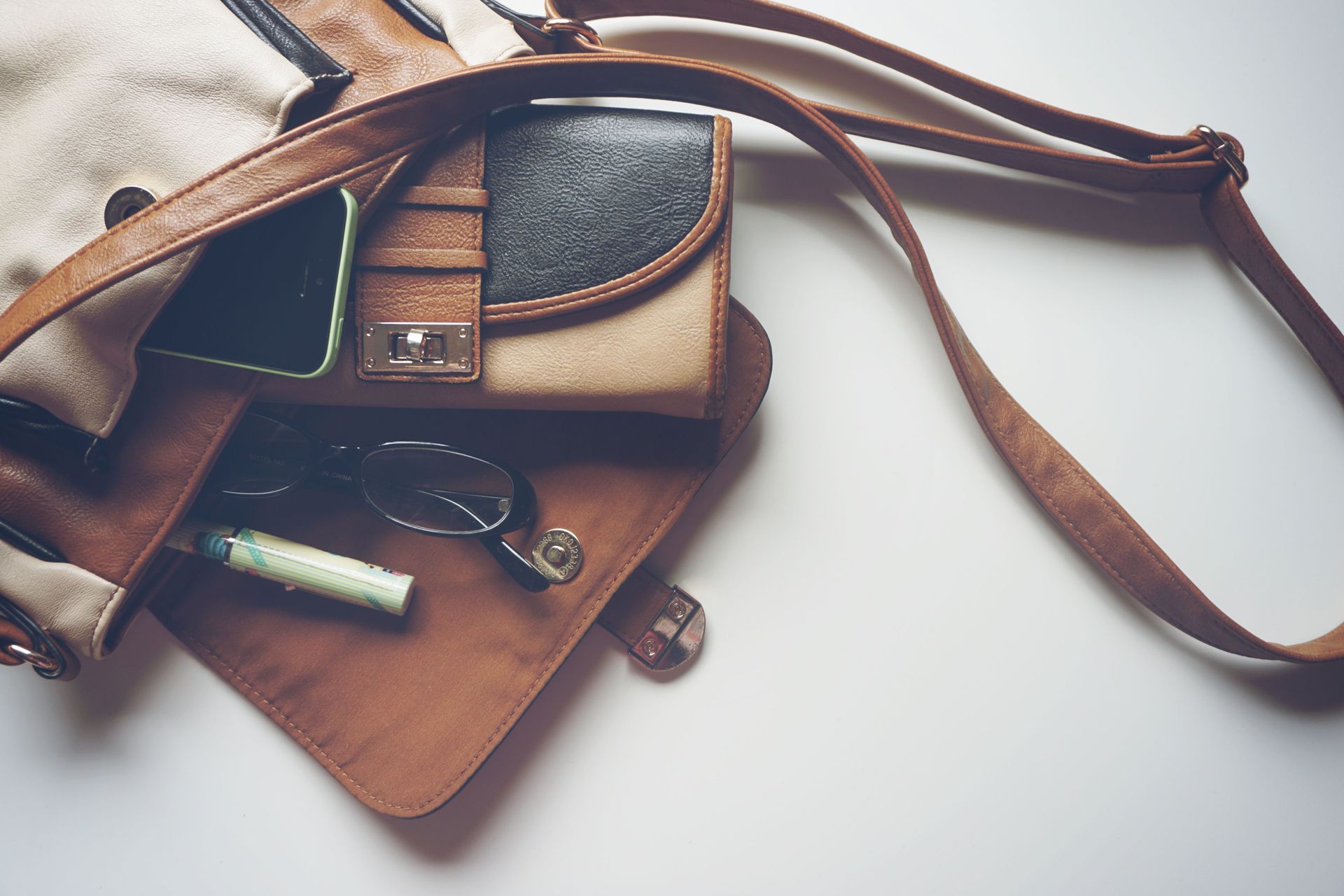 Leather bags and notebook with a pen, arranged on a white surface