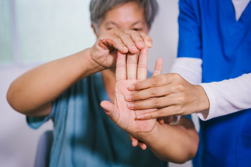 Occupational therapist checking finger and hand mobility with a senior patient