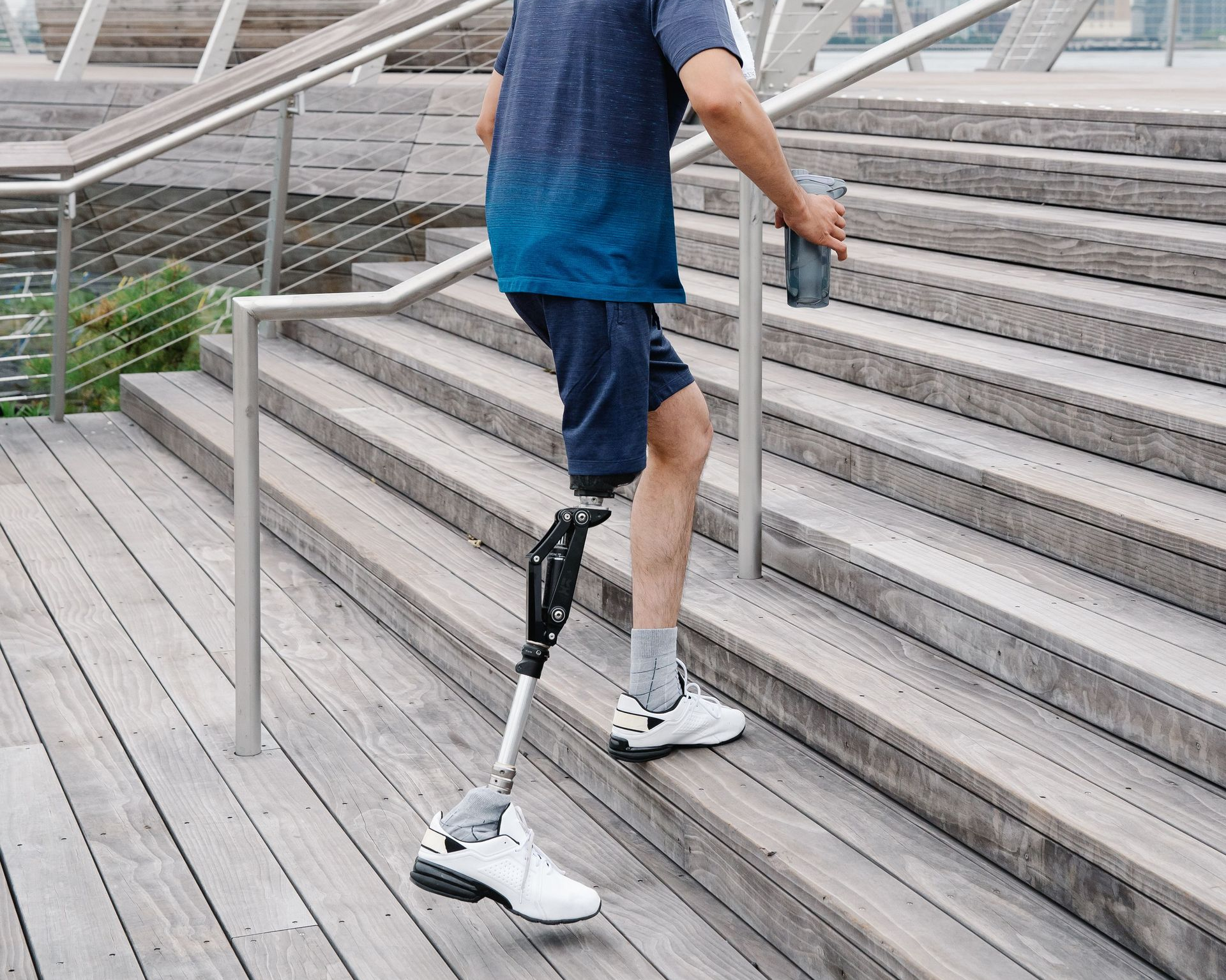 Adaptive mobility and stair safety training Man with a leg amputation using a handrail to walk up stairs
