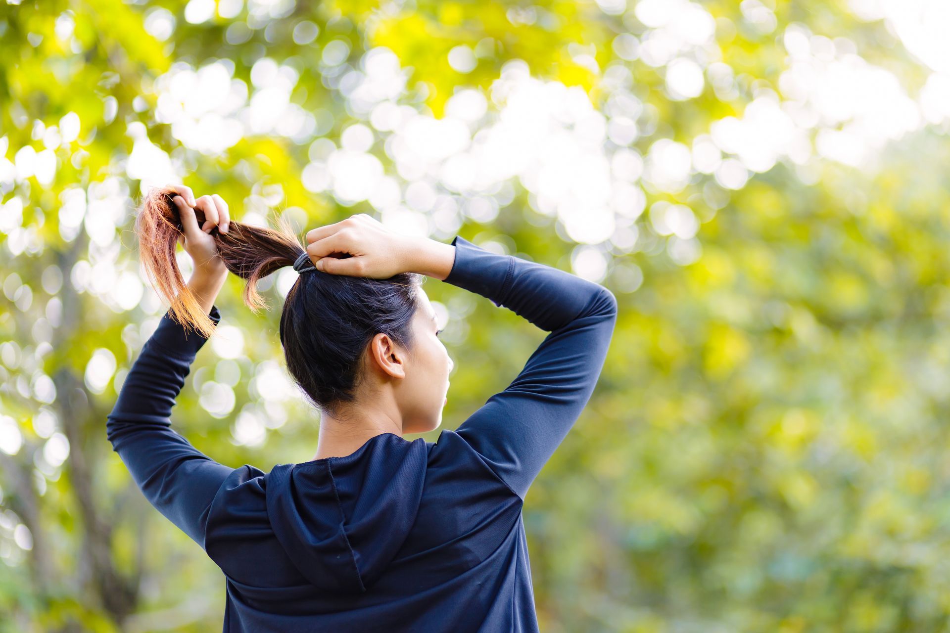 Energy-saving grooming techniques Woman putting her hair up, demonstrating a grooming task that can be adapted to conserve energy