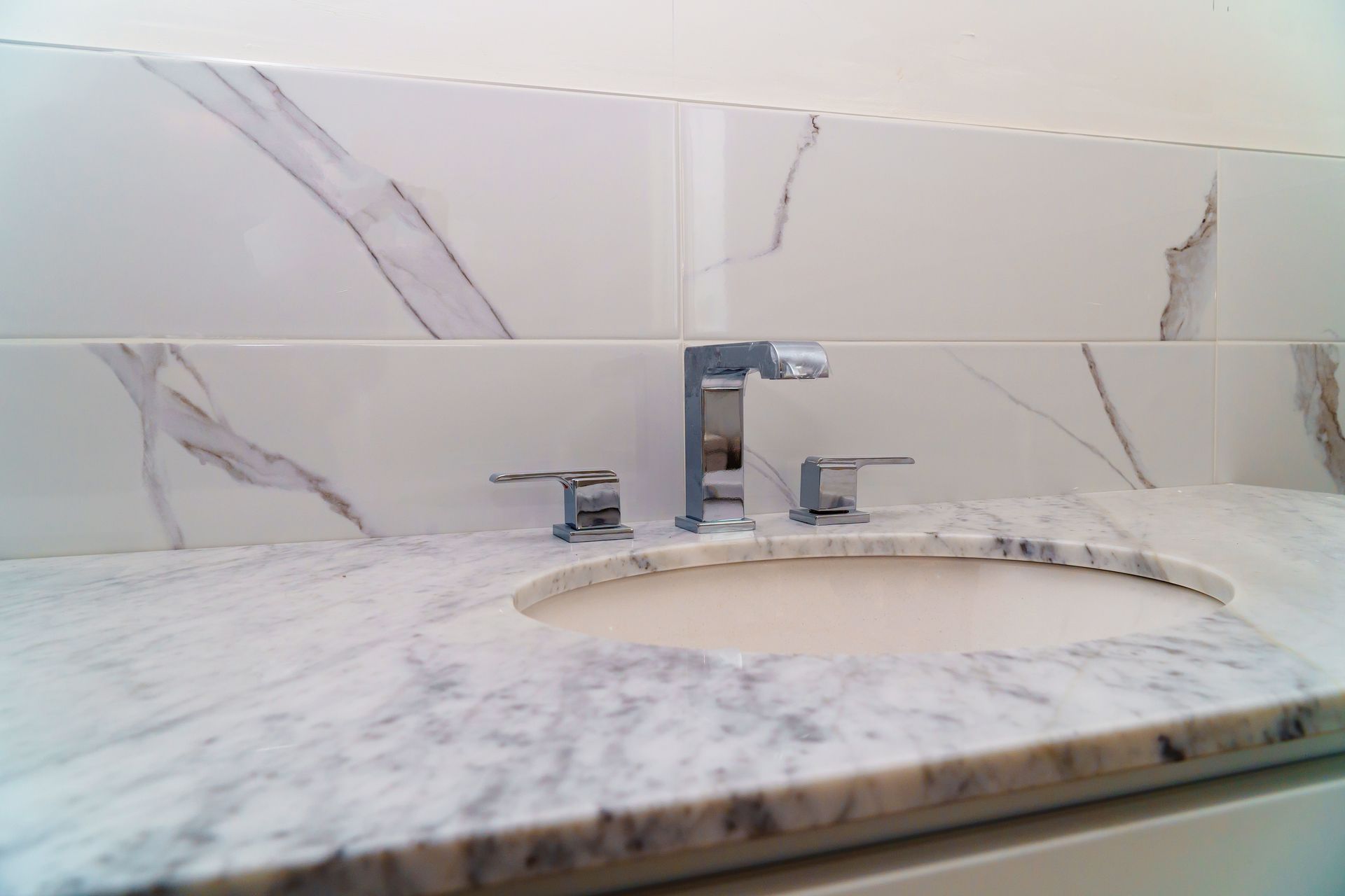 Bathroom sink with marble countertop, white tiles, and chrome faucet. Bathroom sink with marble countertop, white tiles, and chrome faucet.