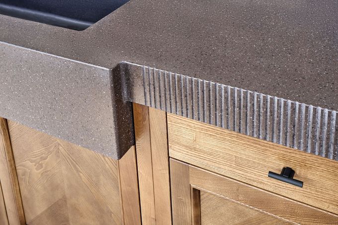 Butcher block countertop in a mint-green kitchen, with white tiled backsplash and sunlight.