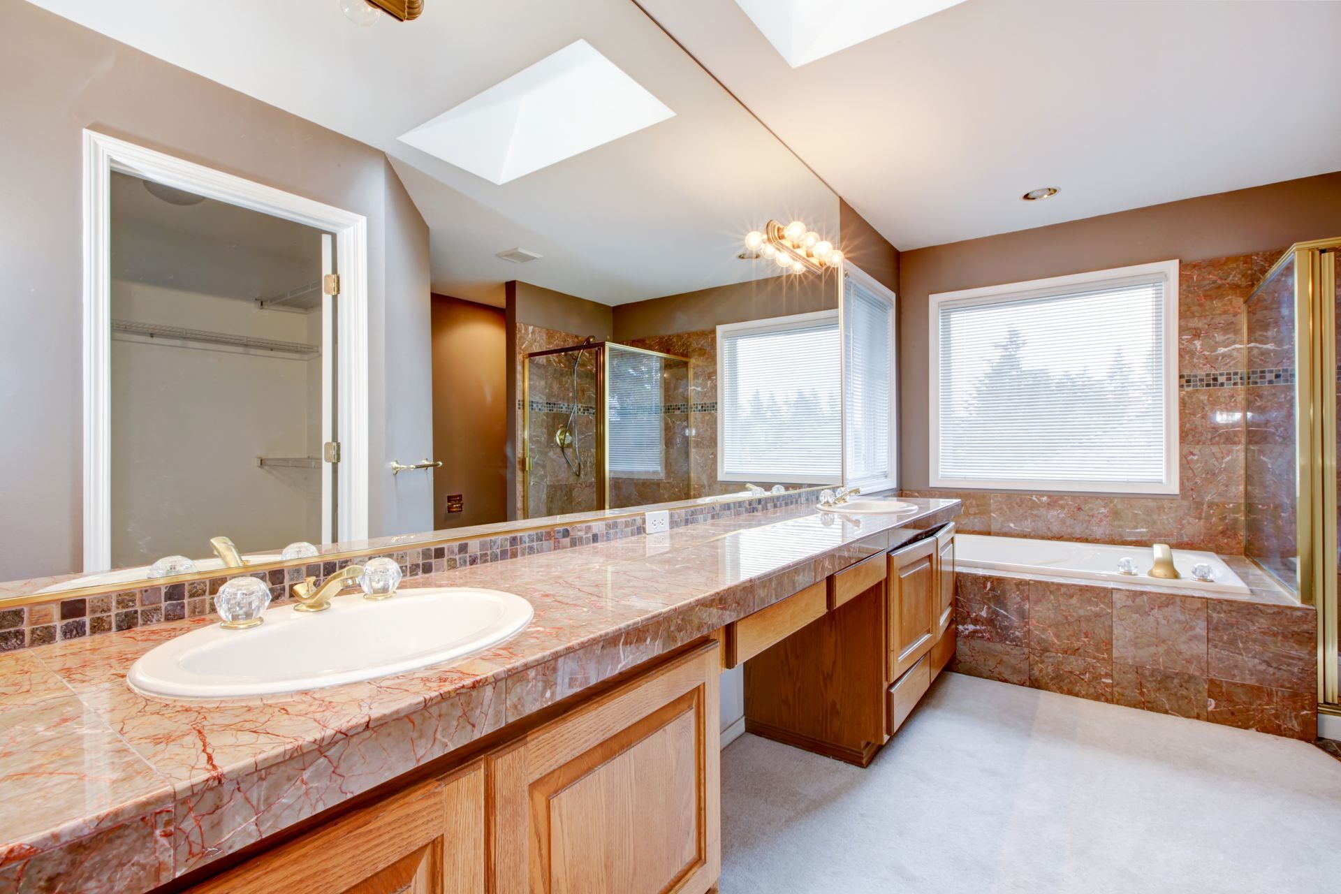 Bathroom with marble countertops, large mirror, tub, shower, and window. Bathroom with marble countertops, large mirror, tub, shower, and window.