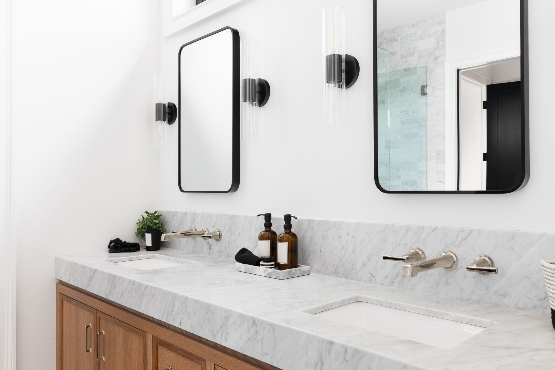 Bathroom with backlit mirror, sink, toiletries, and wall-mounted magnifying mirror. Custom quartz bathroom countertops installed on a double-sink vanity