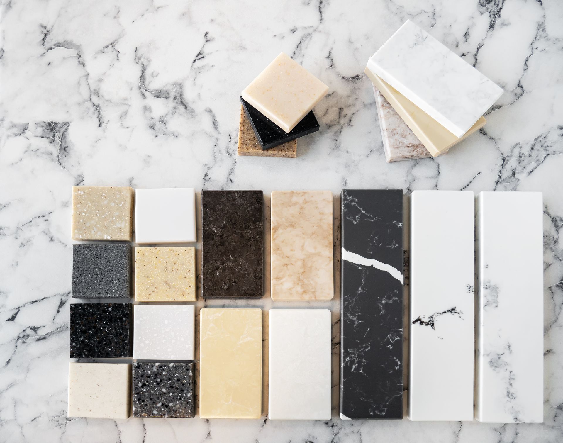 Samples of countertop materials in various colors and textures on a marble surface. Samples of countertop materials in various colors and textures on a marble surface.
