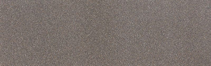 A close-up of a textured, grey-brown surface with a granular appearance, resembling fine sand or stone.