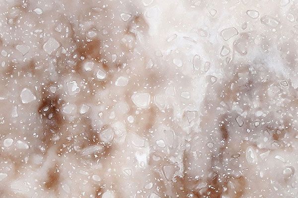 Abstract texture of beige and white marble with scattered specks and irregular shapes.