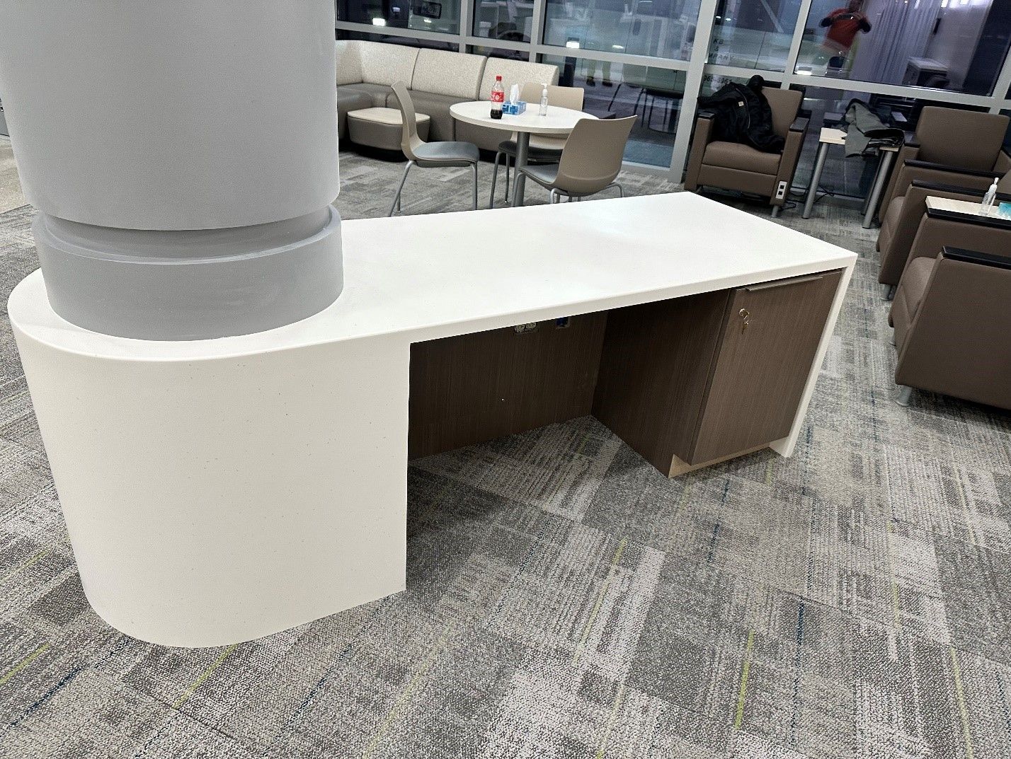 White desk with curved side, near a pillar, in a seating area.