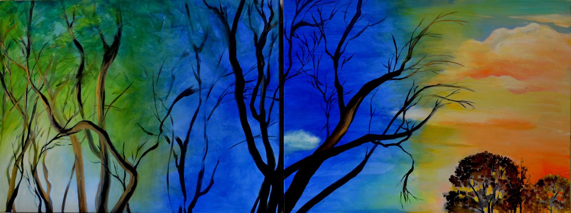 Bare trees silhouetted against a vivid blue, green, and orange sunset sky