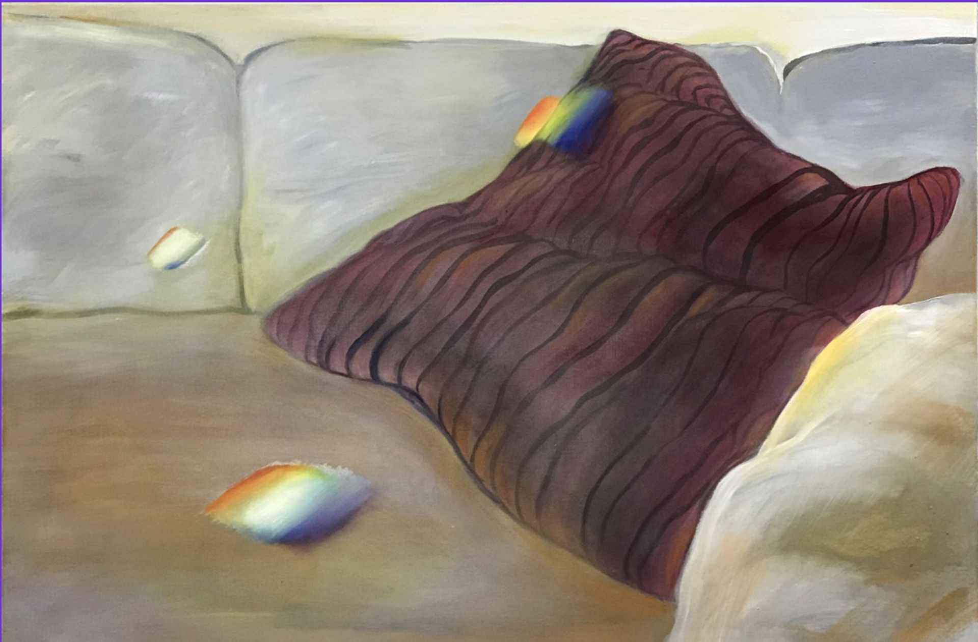 Gray couch with a dark purple pillow and a small rainbow light reflection nearby