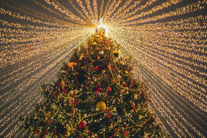 Christmas tree glowing with warm lights and red ornaments, topped by a bright starburst