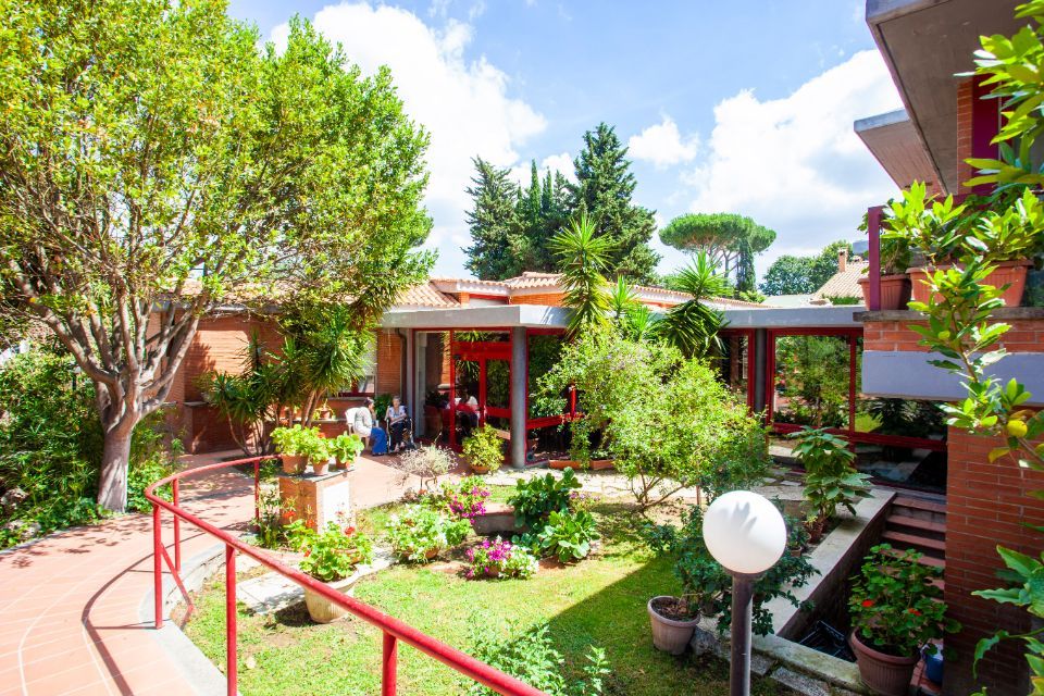 Un grande edificio in mattoni con davanti un rigoglioso giardino verde.