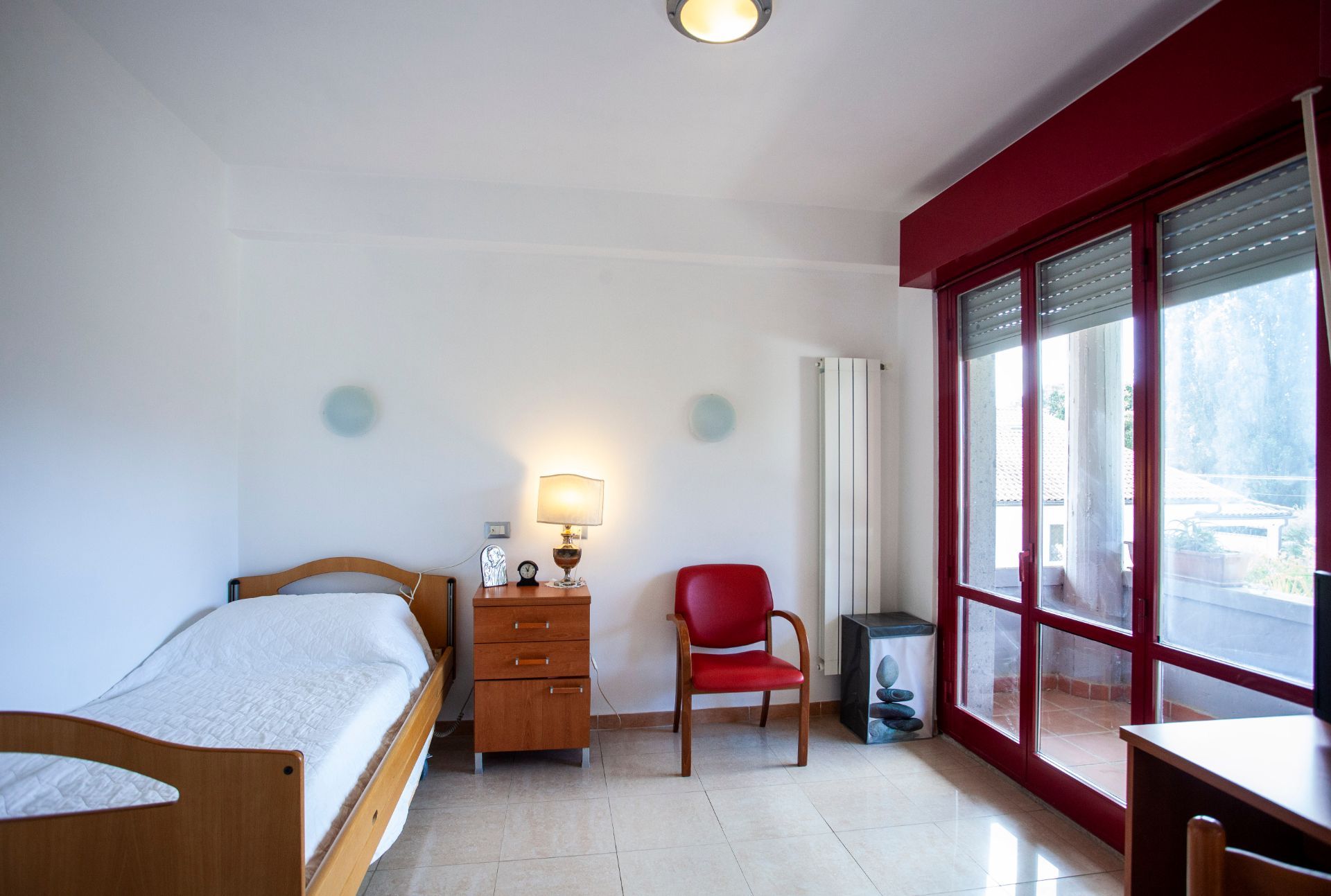 Una camera con un letto singolo e una sedia rossa