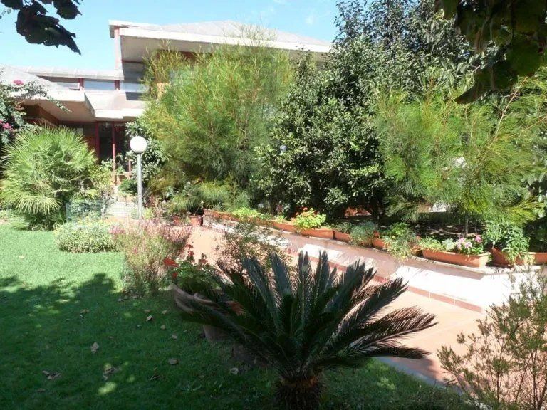 Una grande casa è circondata da un rigoglioso giardino verde