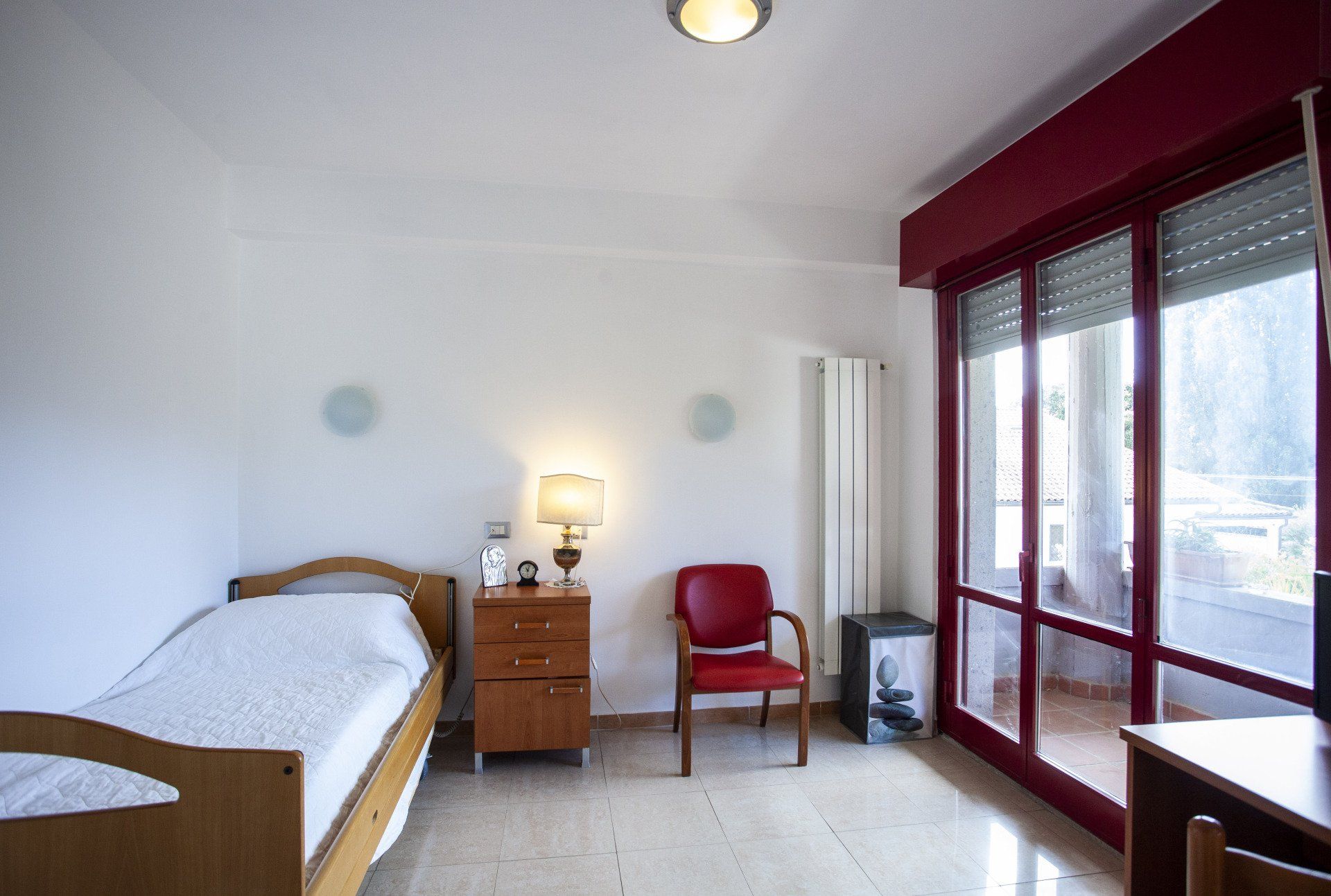 Una camera con un letto singolo e una sedia rossa