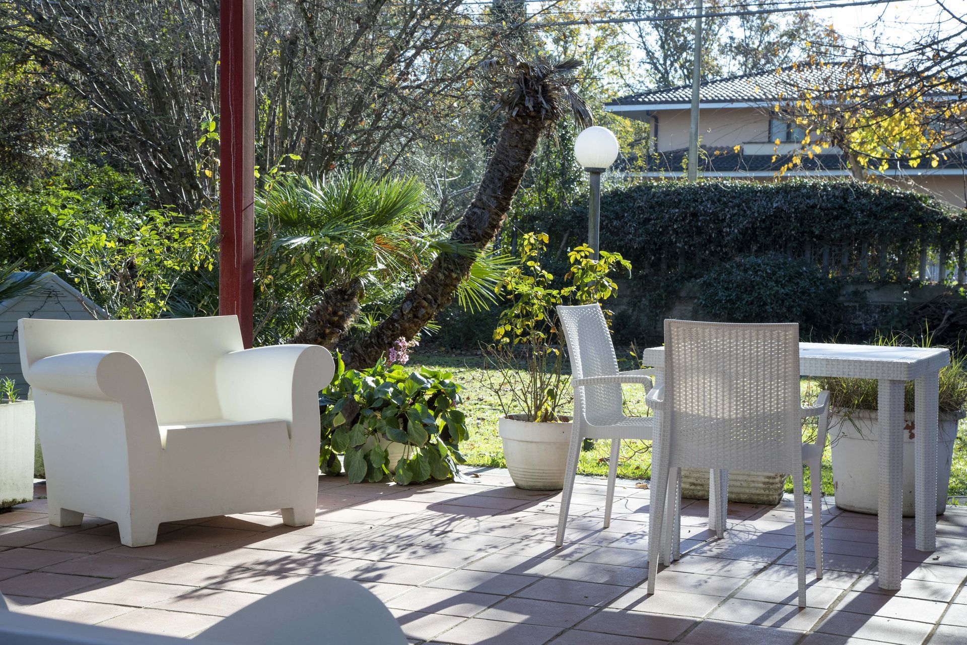 Un patio con sedie bianche e un tavolo con piante in vaso