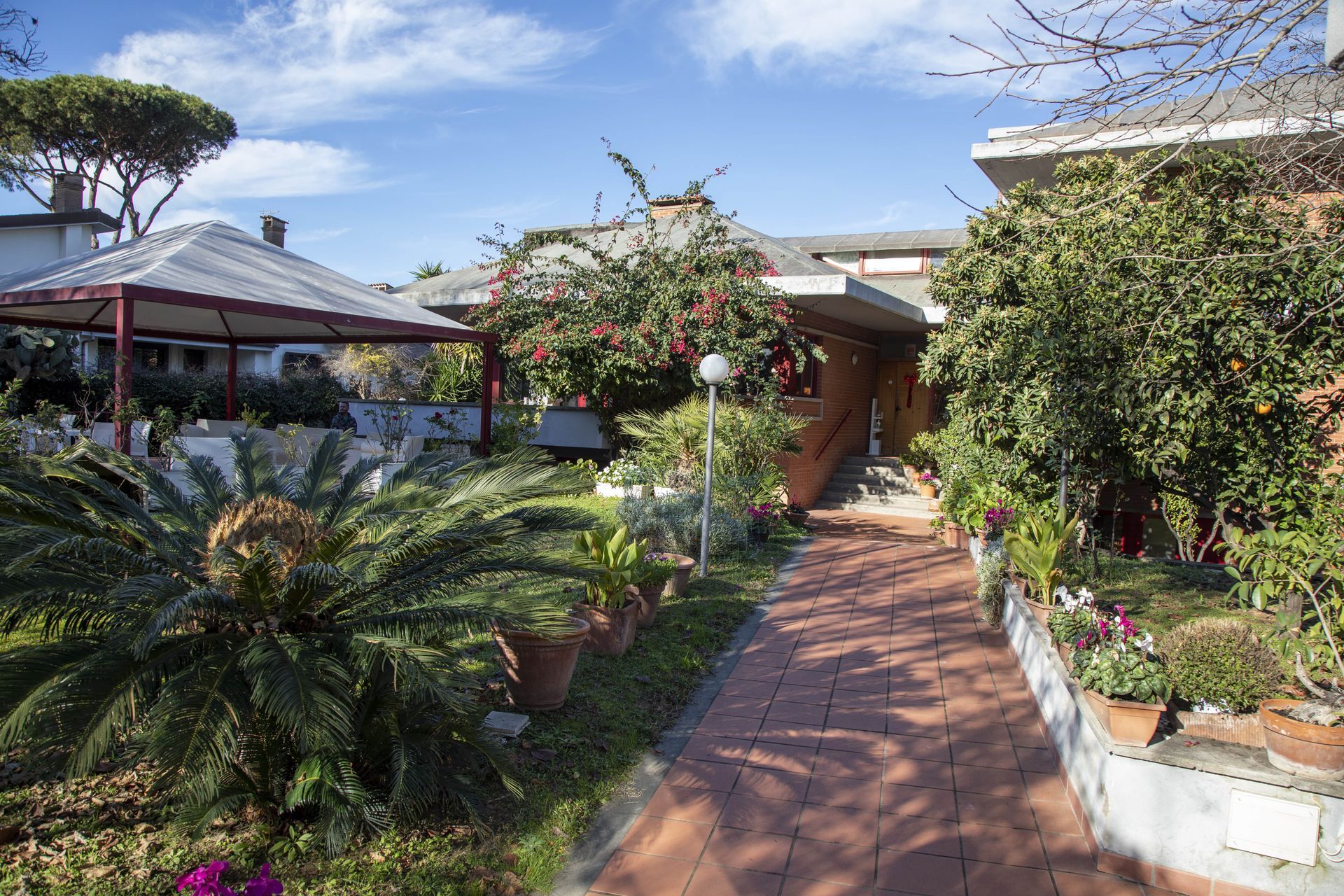 Una passerella in mattoni conduce ad una casa con un gazebo sullo sfondo