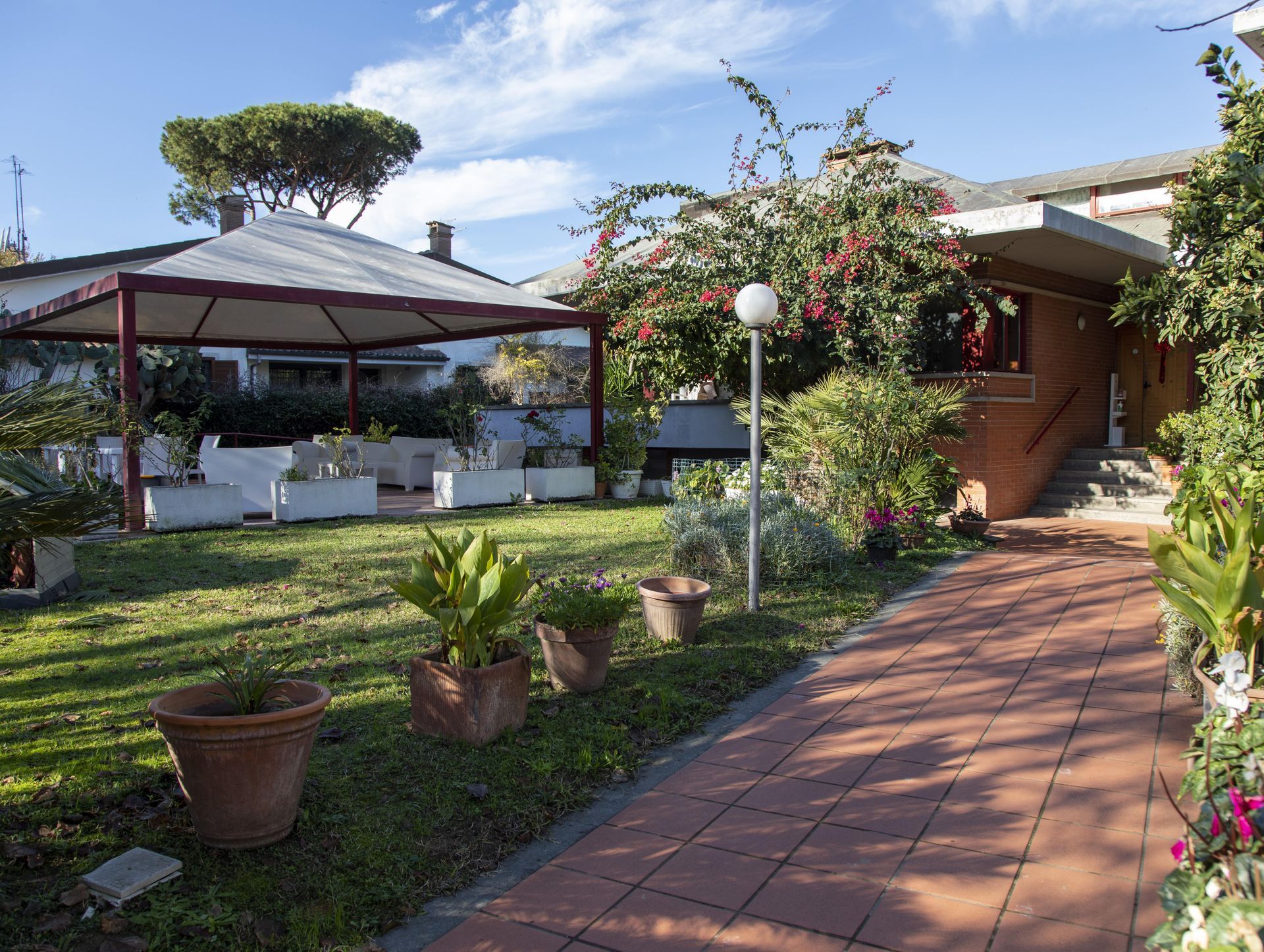 Una passerella in mattoni conduce ad una casa con un gazebo sullo sfondo