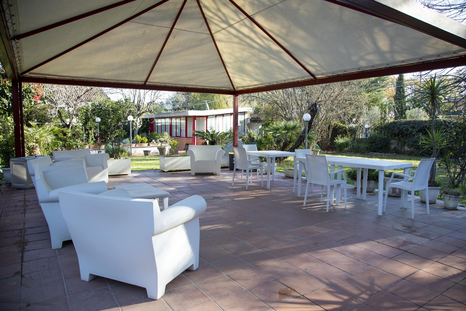 Un patio con sedie e tavoli bianchi sotto una tenda.