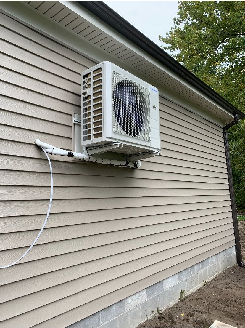 An air conditioning unit mounted on the siding of a building.