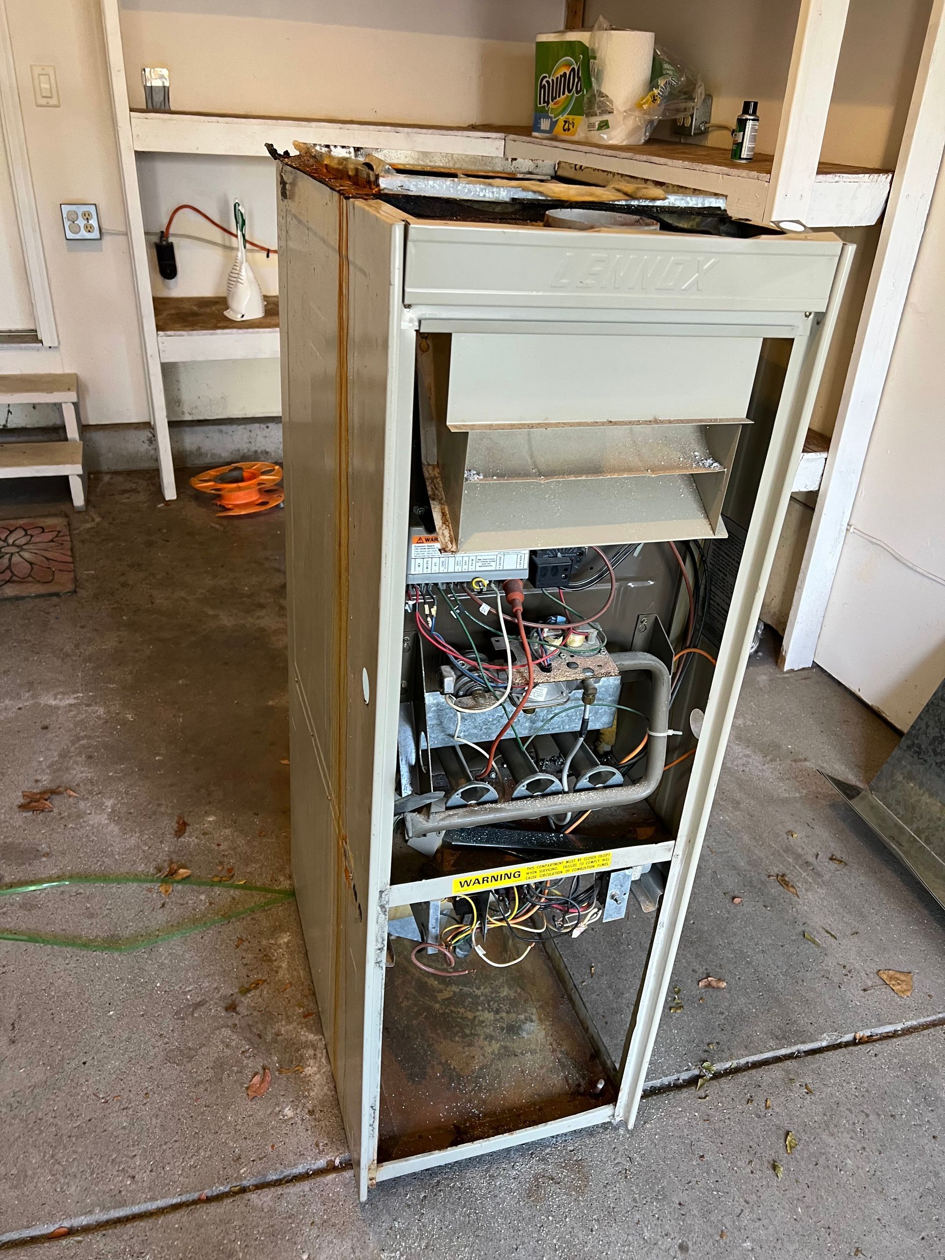 Open furnace with exposed internal components, in a garage.