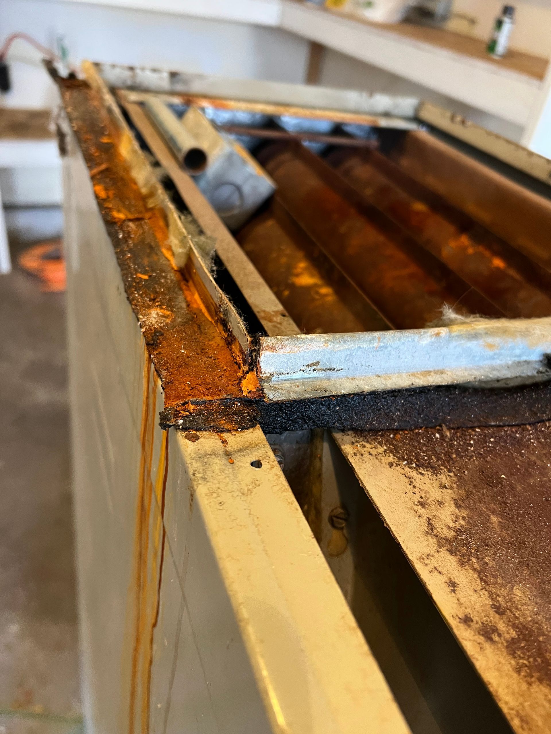 Rusted metal industrial component with visible corrosion. Light-colored exterior with a damaged internal structure.