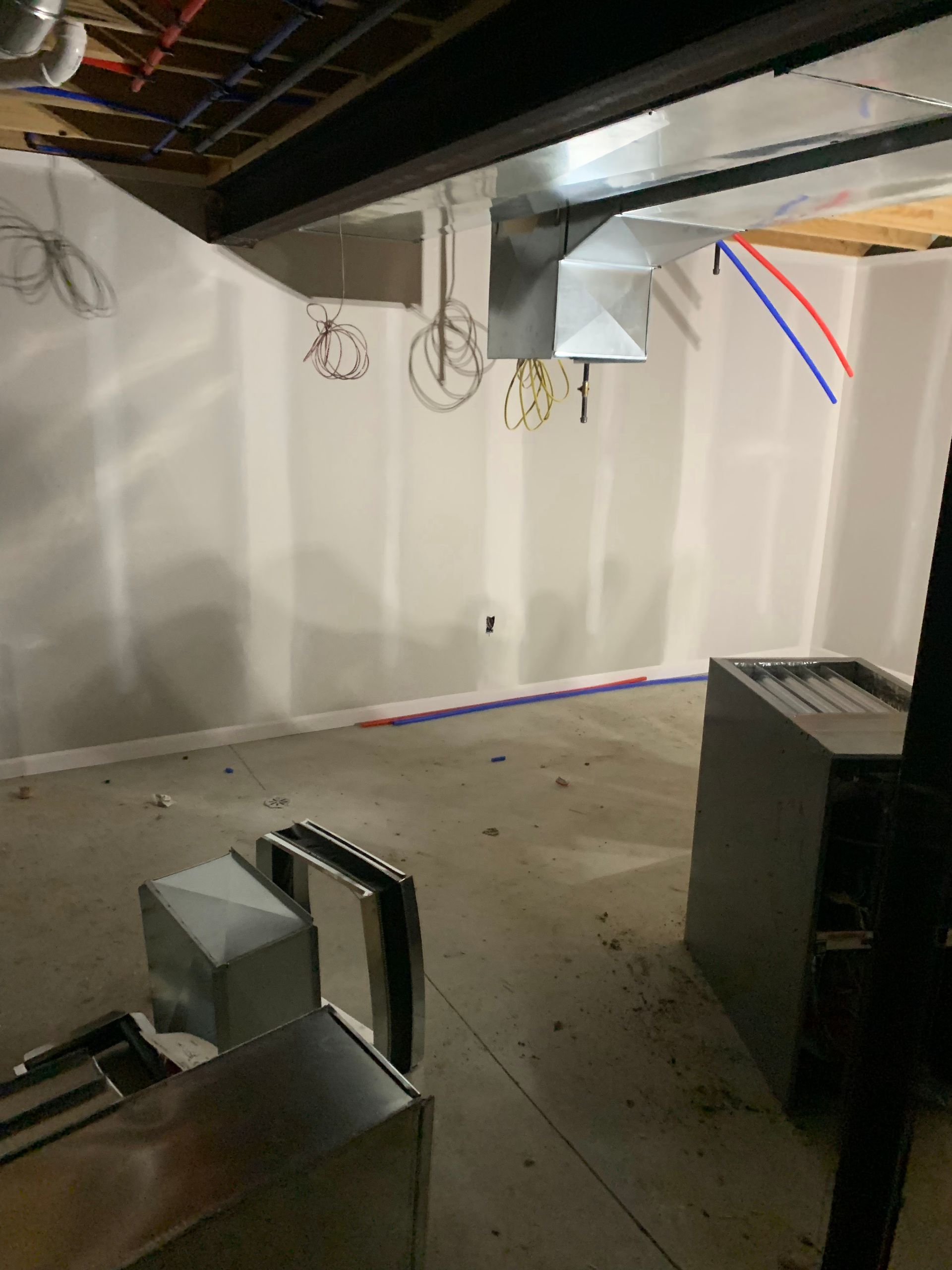 Basement with unfinished drywall, HVAC ductwork, and water pipes. Metal boxes and furnace are present.