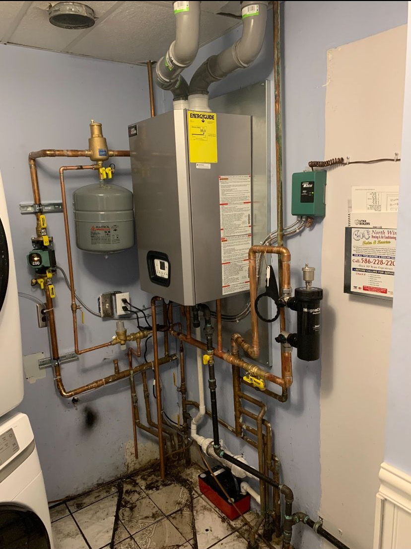 A complex system of pipes and equipment, likely a boiler or HVAC system, installed against a wall.