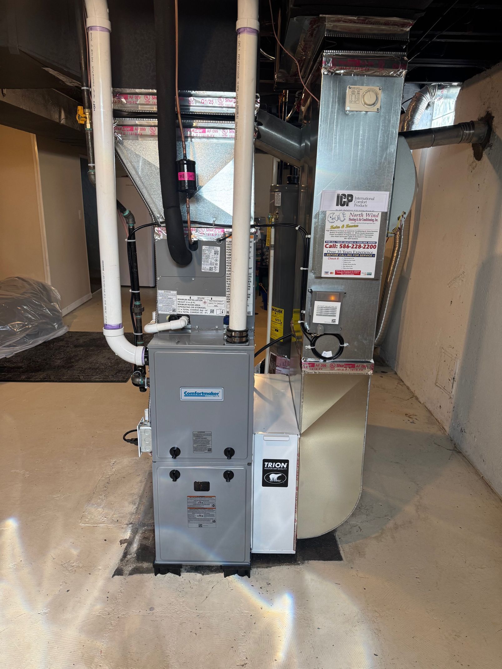 Basement furnace and HVAC equipment with pipes and ductwork along the wall
