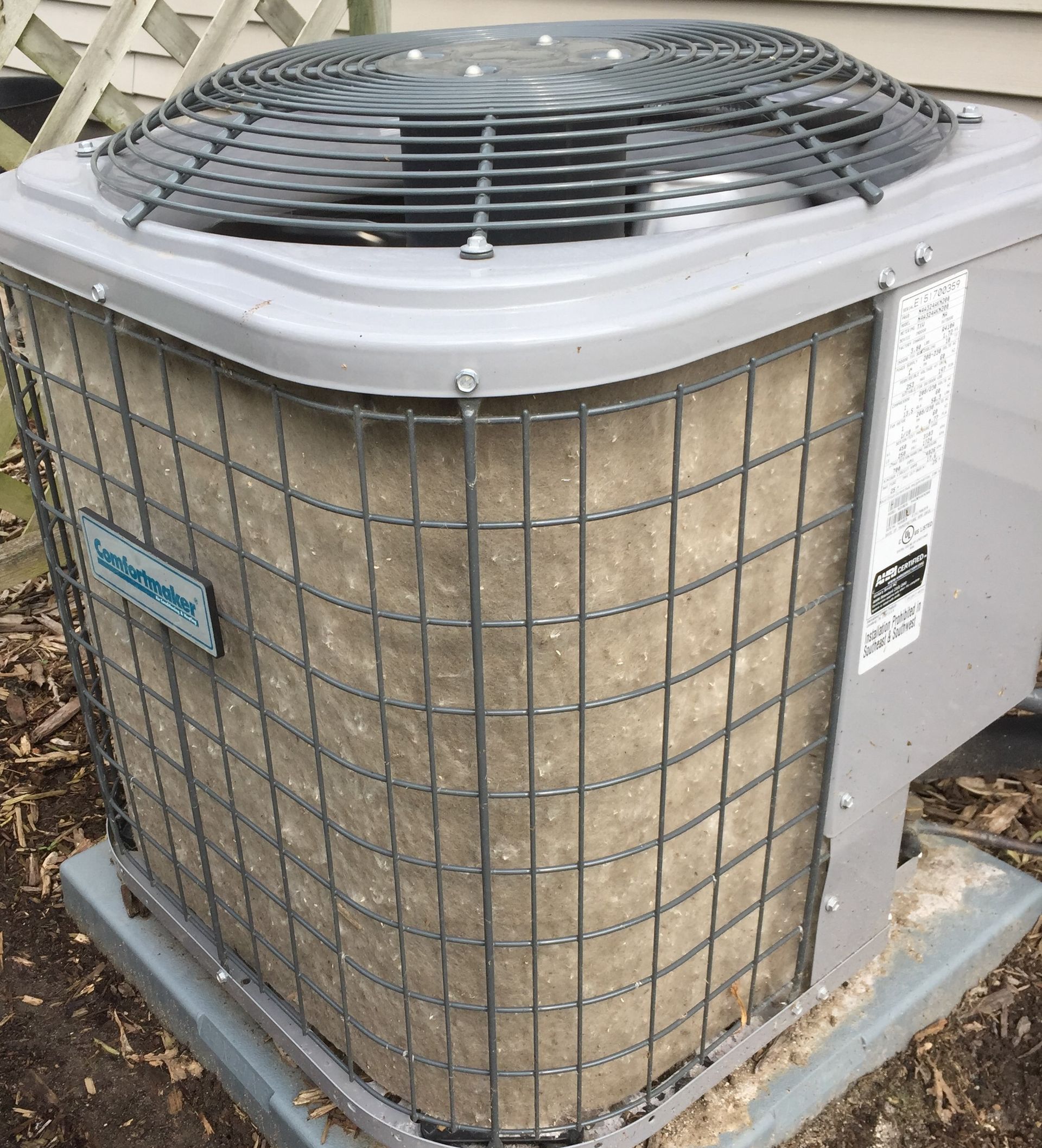 Air conditioner unit with dirty, dust-covered coils encased in a wire cage.