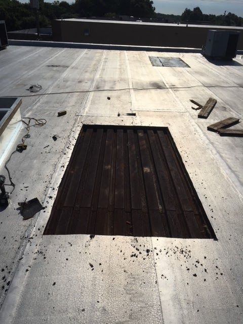 Flat commercial roof with a large, dark rectangular opening.