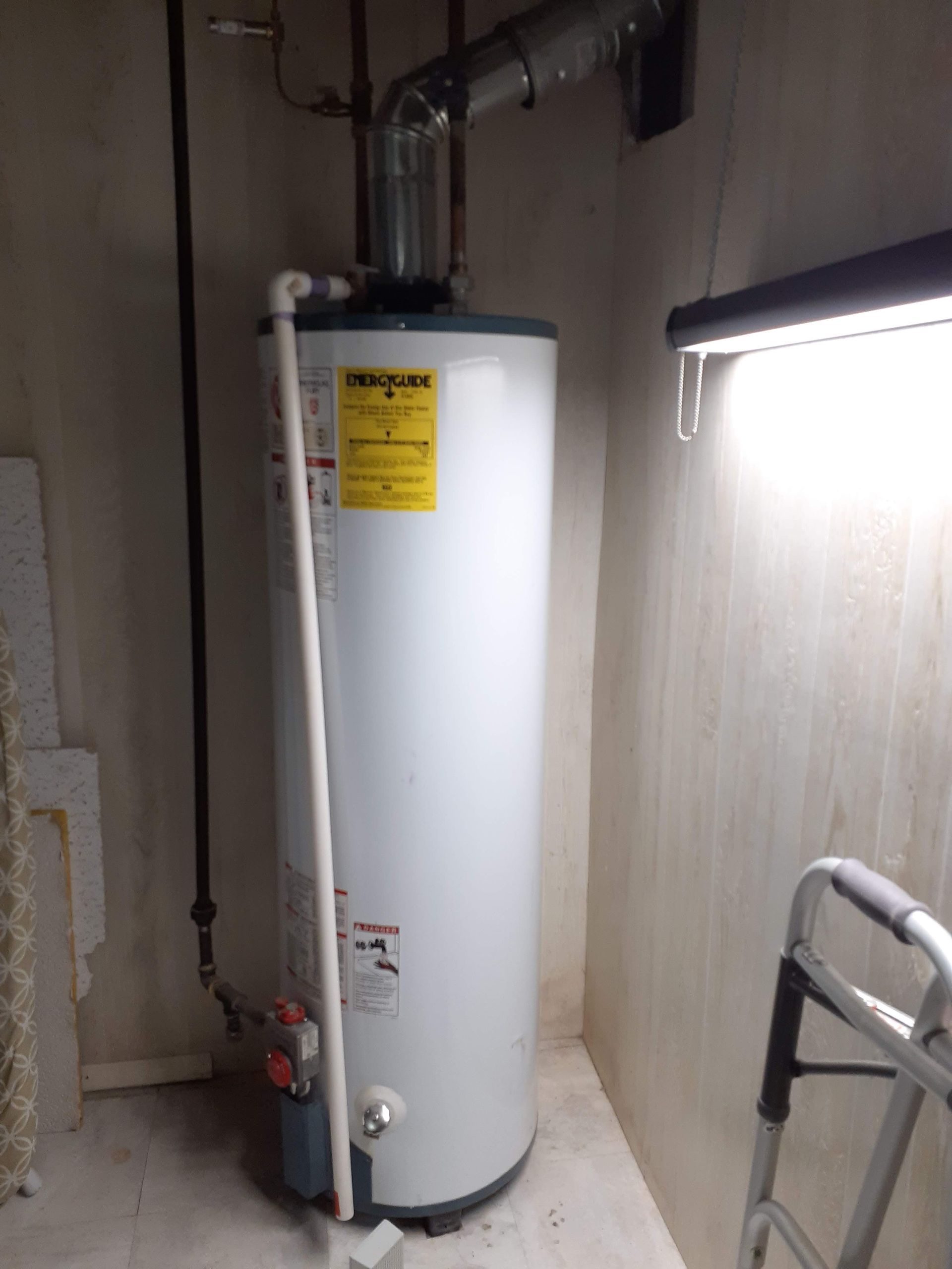 Water heater in a basement corner, with vent pipe and access steps.