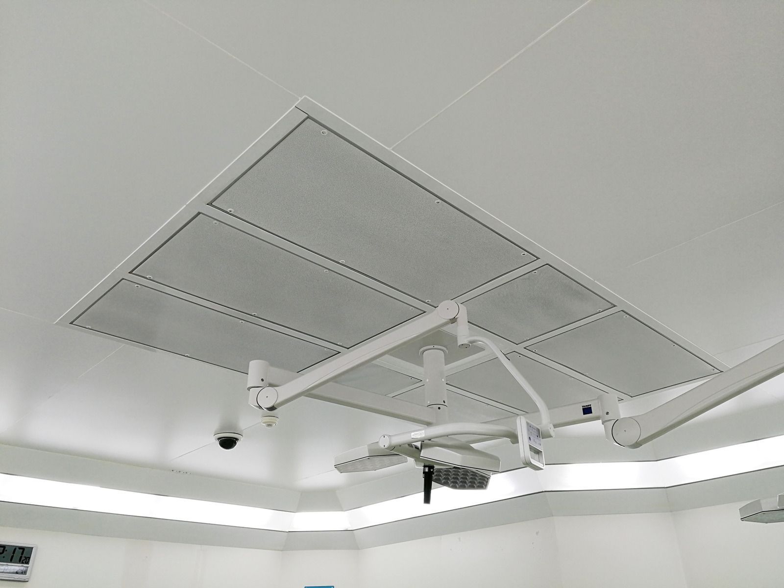 White ceiling with air vents and surgical lights in an operating room.