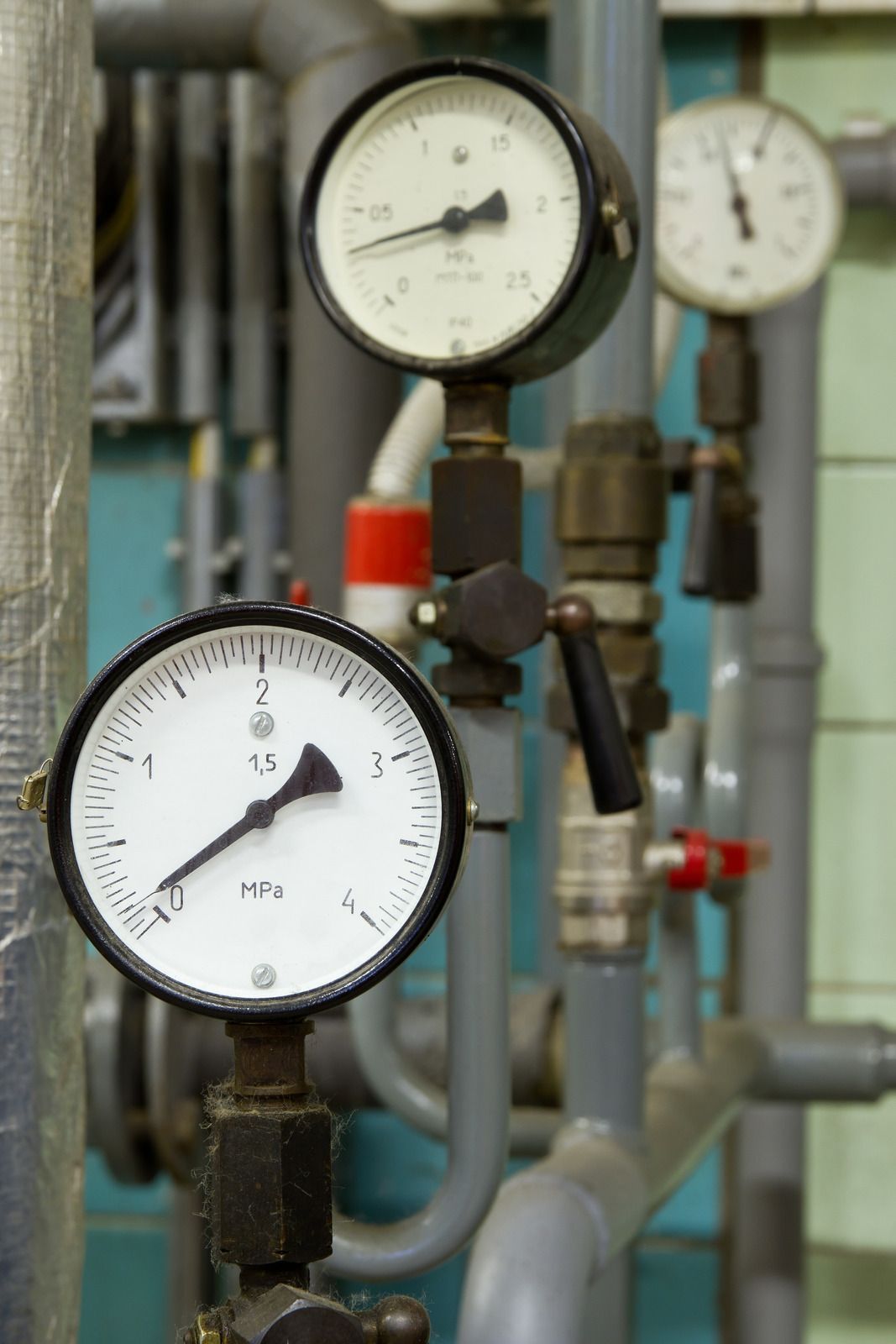 Industrial pressure gauges on metal pipes in a factory setting
