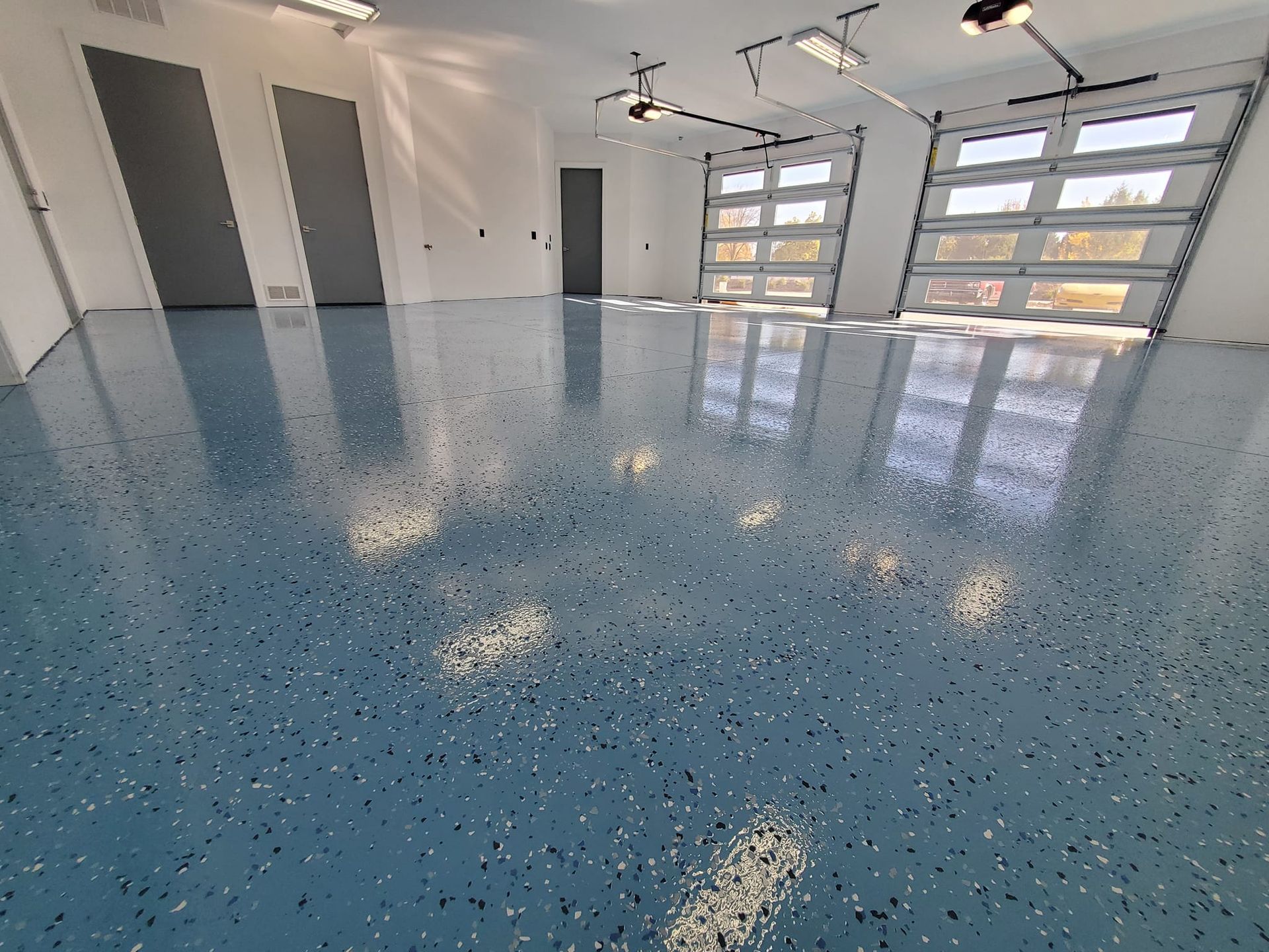 Blue speckled epoxy garage floor with three doors and two garage doors.