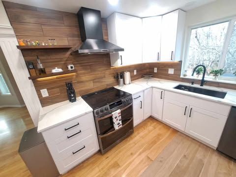 Modern kitchen with gray and white cabinets, wood countertops, and built-in appliances.