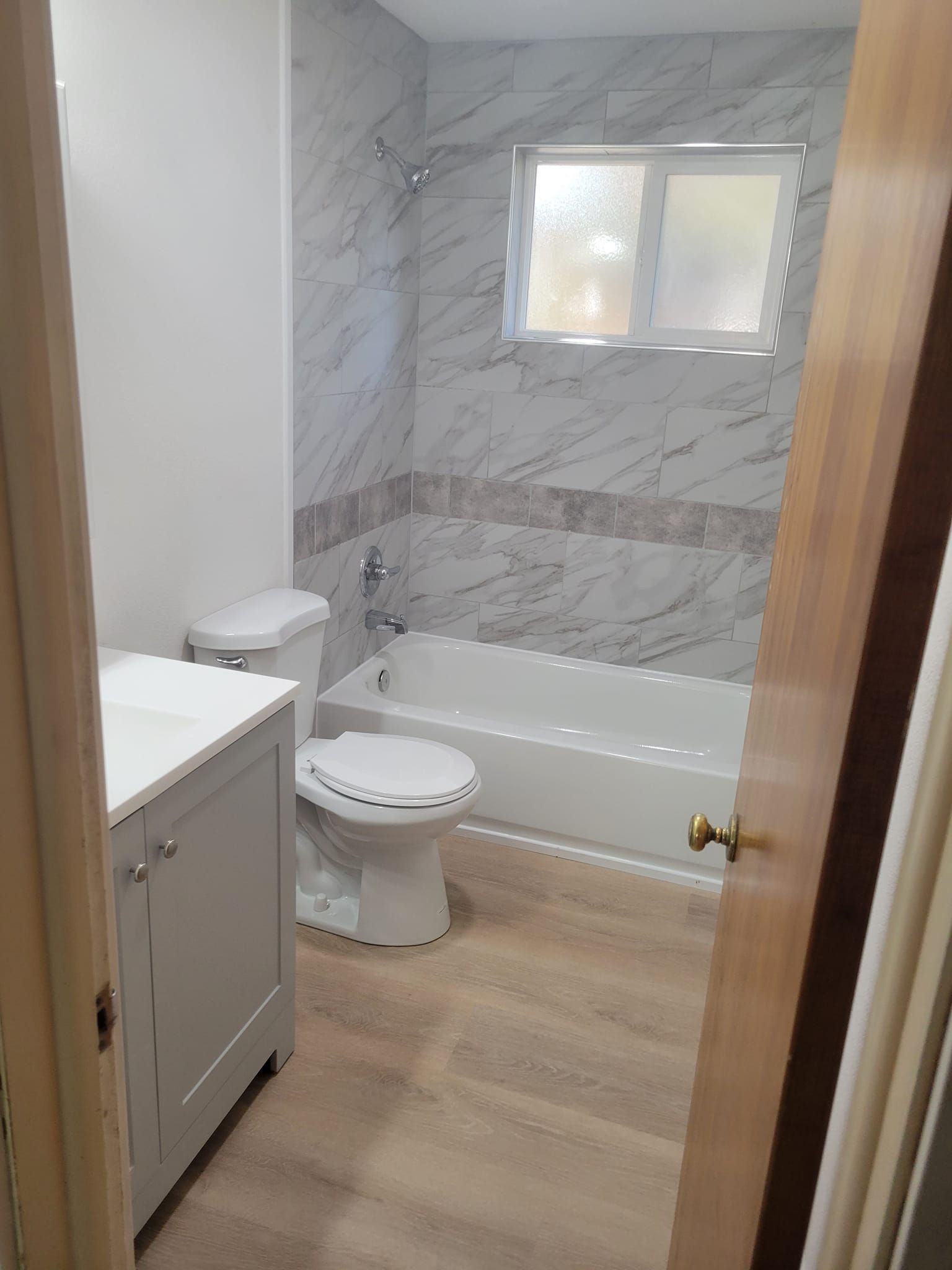 Modern bathroom with walk-in shower, wooden floor, gray sink, and large mirror.