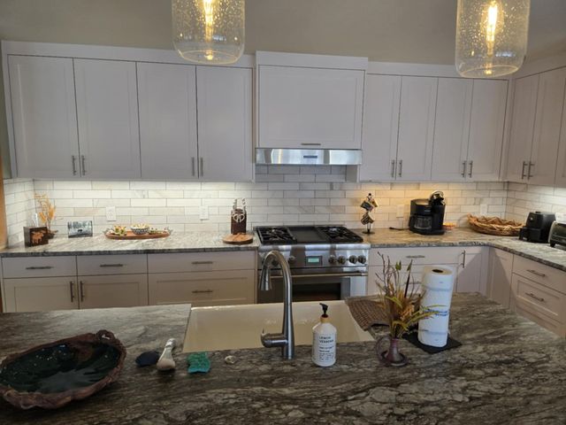 Modern kitchen with white cabinets, granite countertops, and stainless steel appliances.