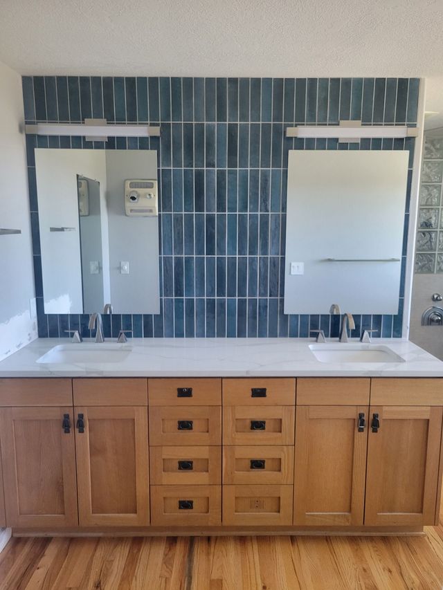 Modern bathroom with gray tiles, white vanity, large mirror, and glass shower.