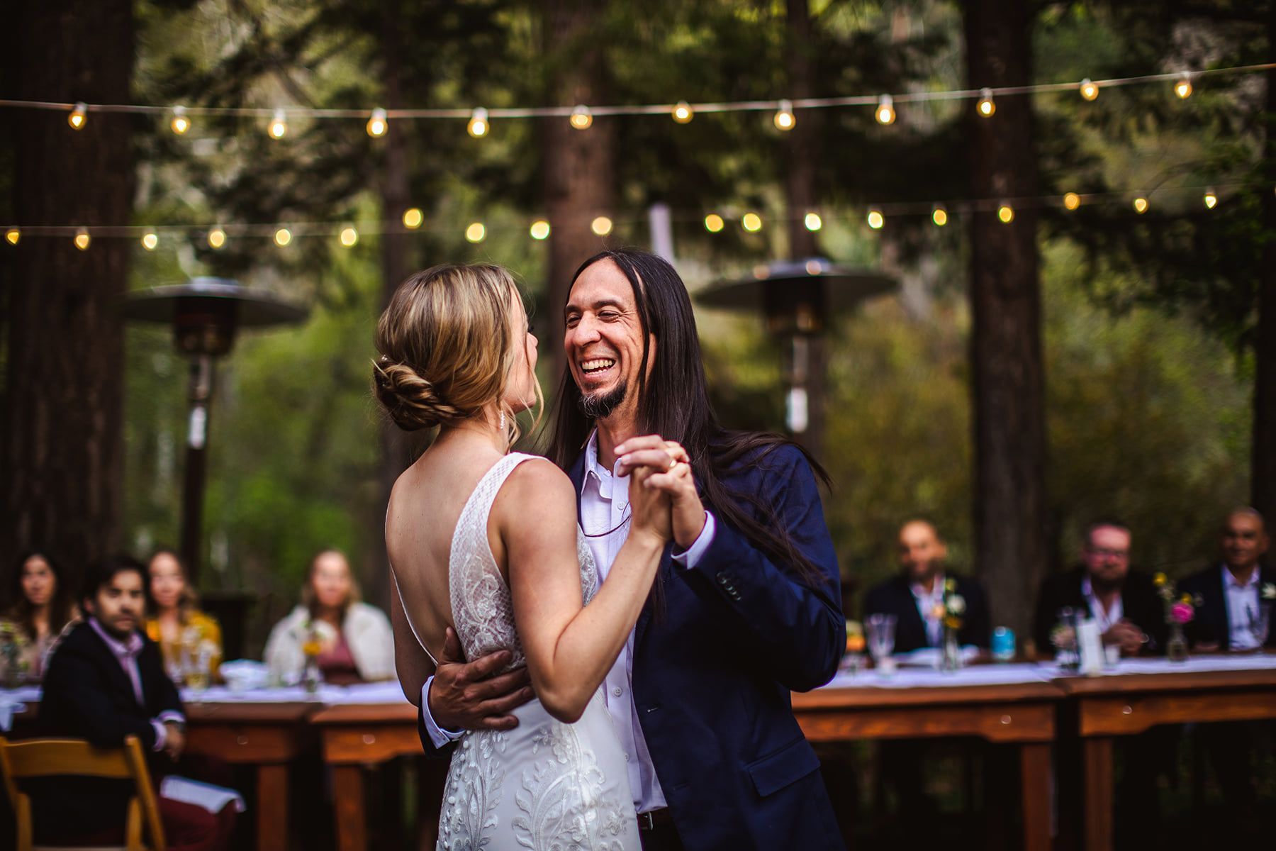 Bride and groom dancing under string lights at an outdoor reception
