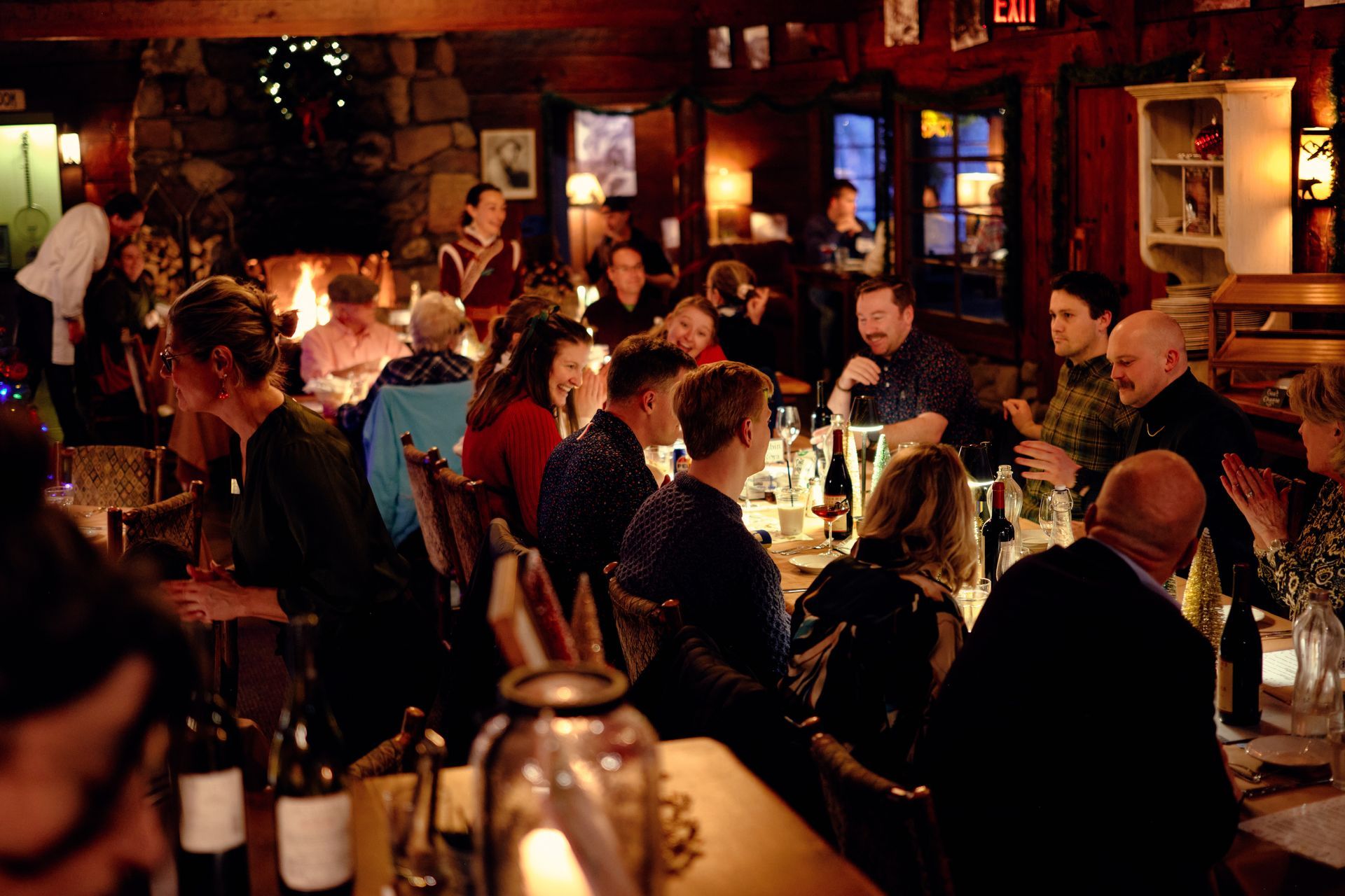 Crowded candlelit restaurant with people dining at tables and warm ambient lighting