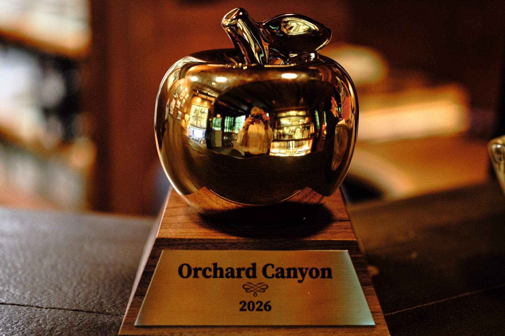 Gold trophy on a plaque labeled “Orchard Canyon 2026” in a warm indoor setting