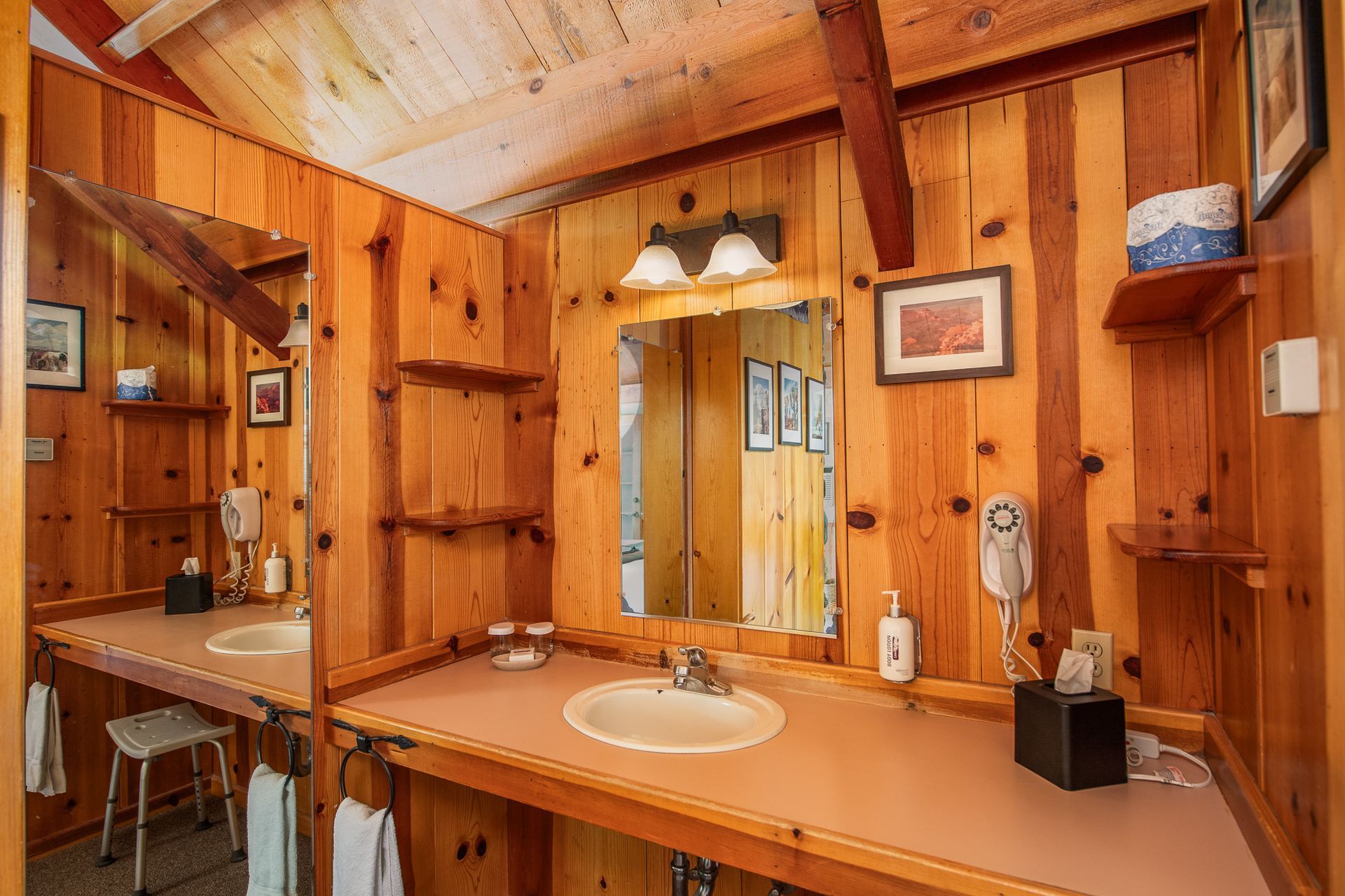 Wood-paneled rustic bathroom with double sinks, mirror, and warm lighting