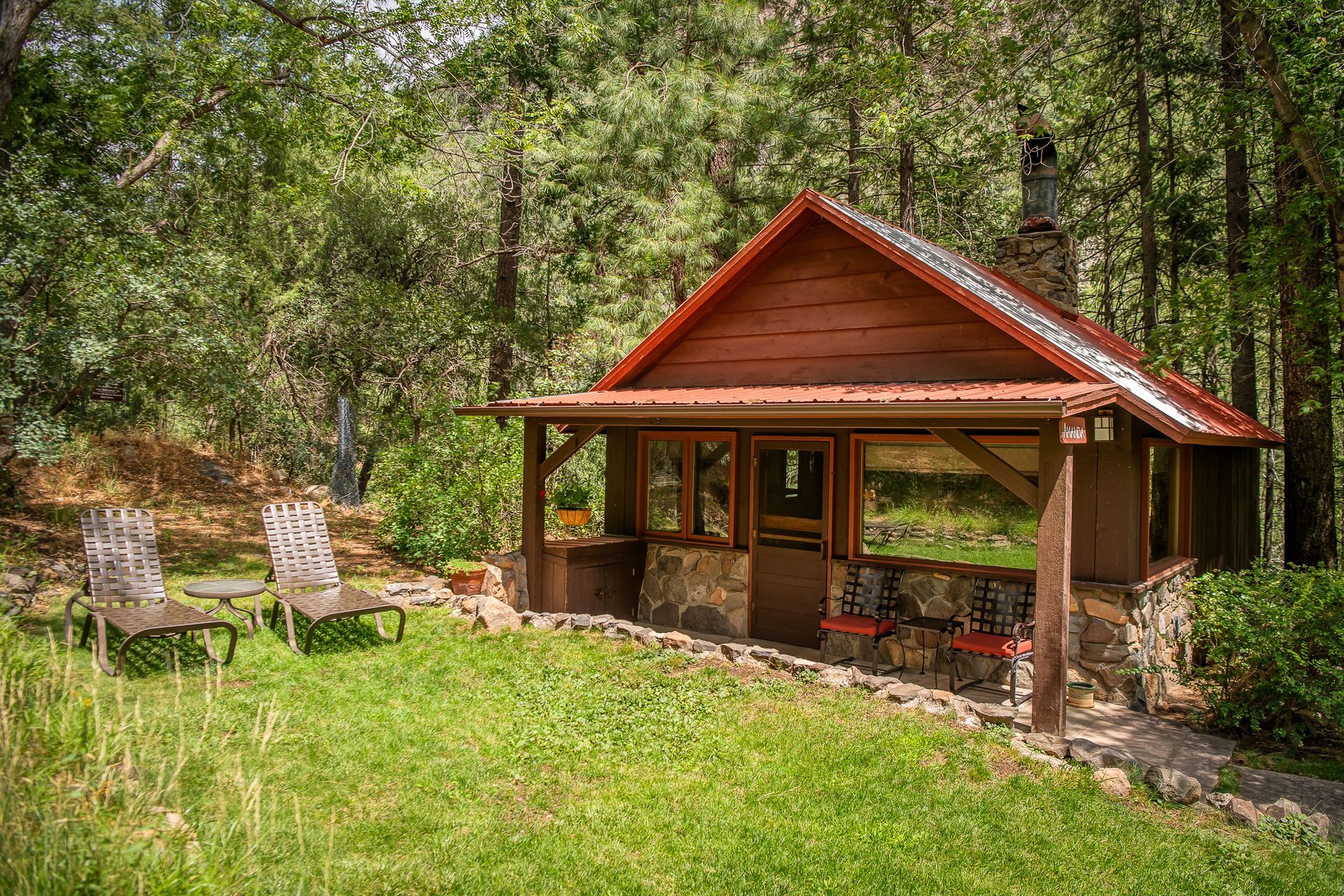 Rustic red-roofed pavilion with open seating in a wooded park clearing