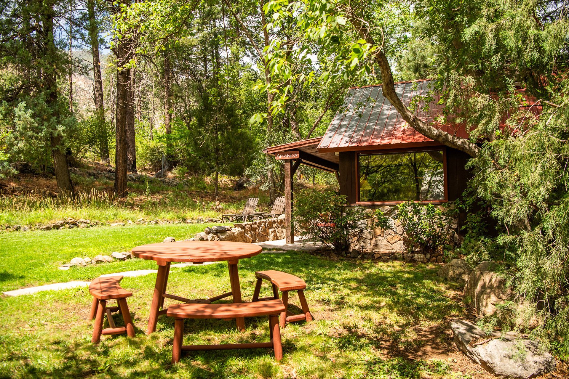 Rustic picnic tables in a sunny green park beside a small gazebo