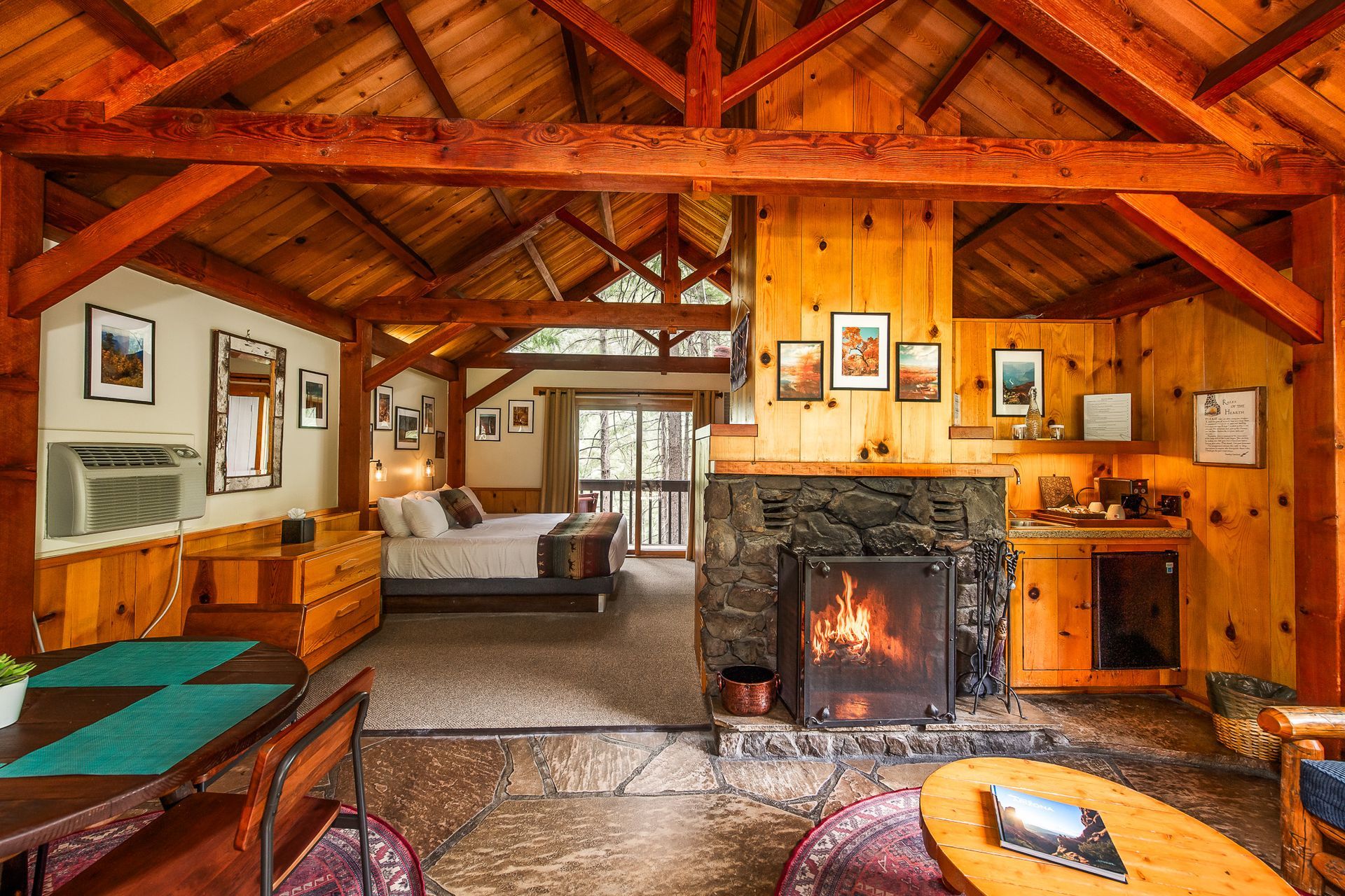 Cozy rustic living room with wooden beams, a lit fireplace, and warm cabin-style decor.