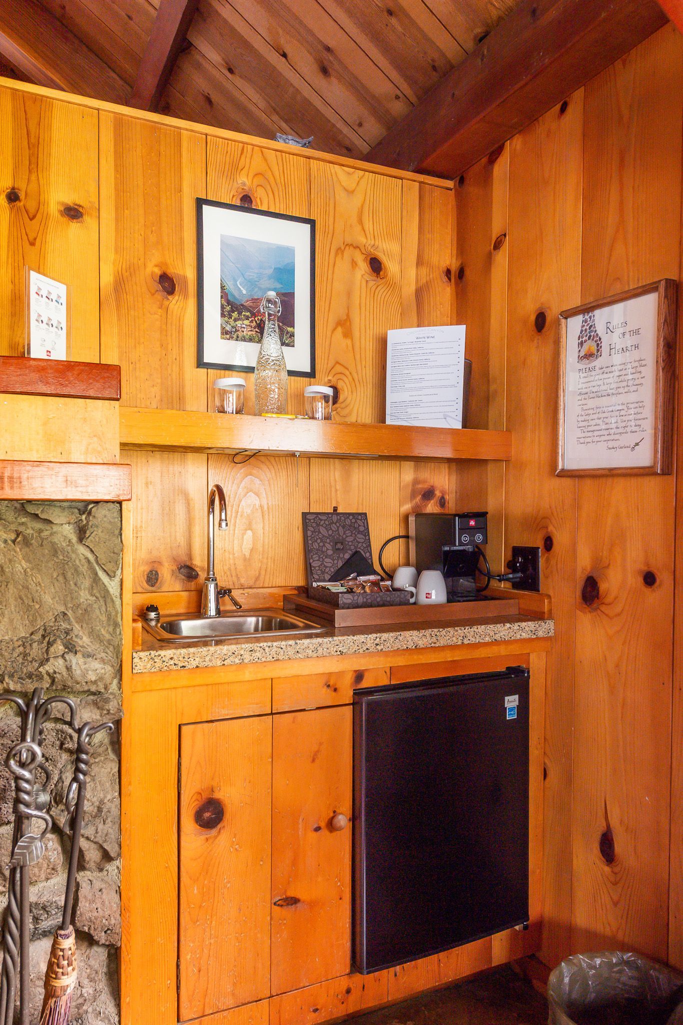 Wood-paneled rustic bathroom vanity with sink, mirror, and black cabinet beneath shelf decor.